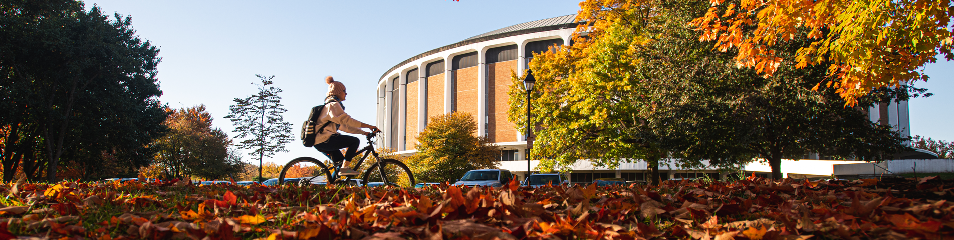 student riding a bike in the fall on campus 
